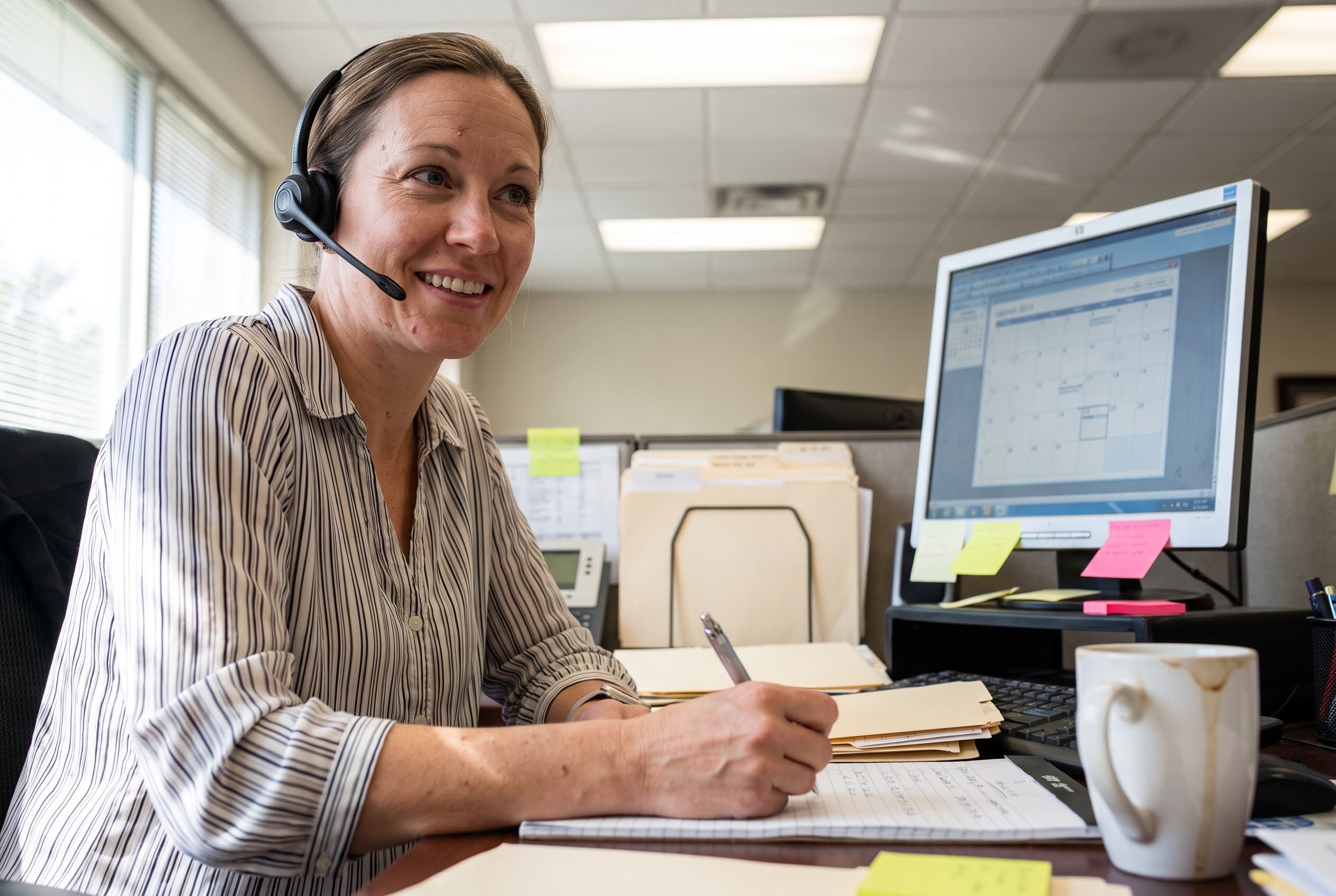 A smiling Lifecare care coordinator wearing a headset, ready to help.